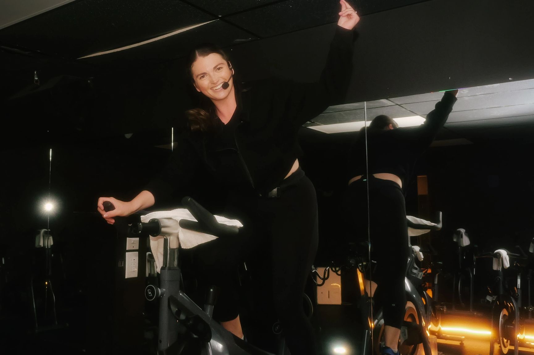 Woman smiling on a stationary bike with a headset.