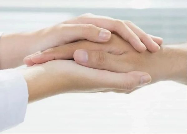 Therapist supporting client by hand holding.