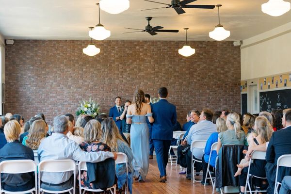A couple walks down the aisle at a wedding ceremony indoors.