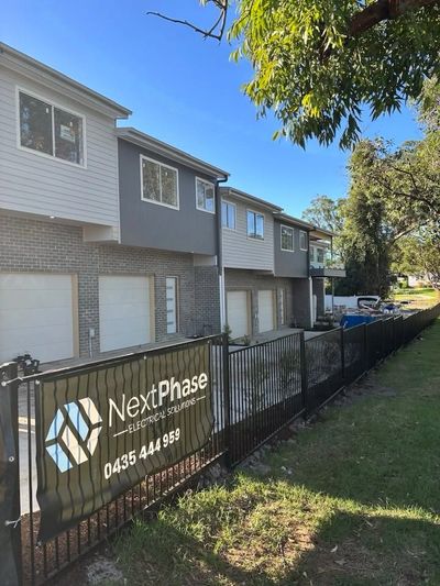 Group of modern townhouses with NextPhase Electrical Solutions sign on fence in Charlestown, NSW.