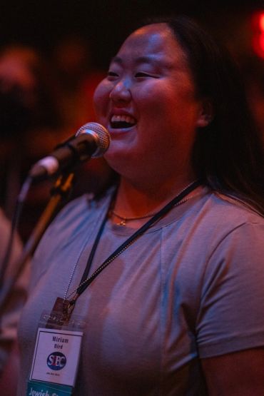 Person smiling while speaking into a microphone.