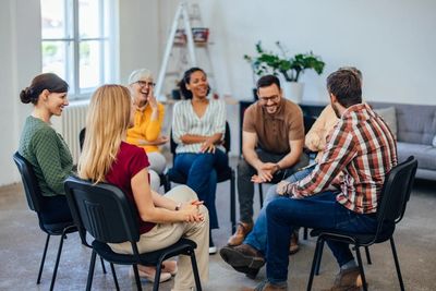 A group of adults sitting in chairs in a circle, engaged in a lively group discussion.