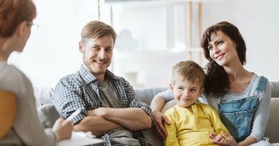 A family smiling during a counseling session with a therapist.