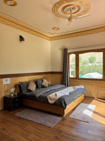 Bright wooden bedroom with a large window and ceiling fan.