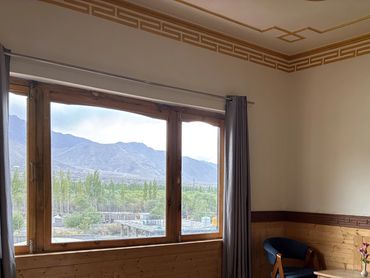 Cozy room with bed, chairs, and a window with mountain view.
