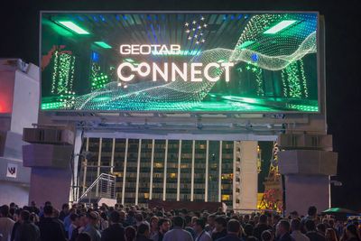 Large digital billboard displaying 'GEOTAB CONNECT' above a crowded nighttime outdoor event.