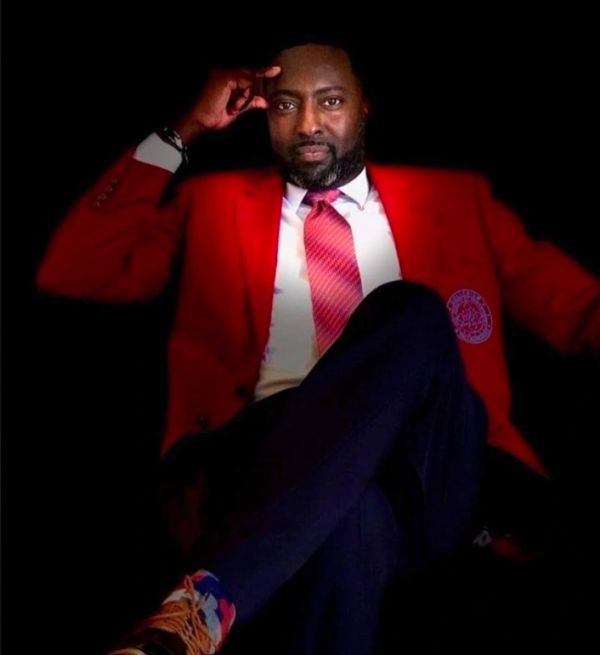 Man in red blazer seated confidently.