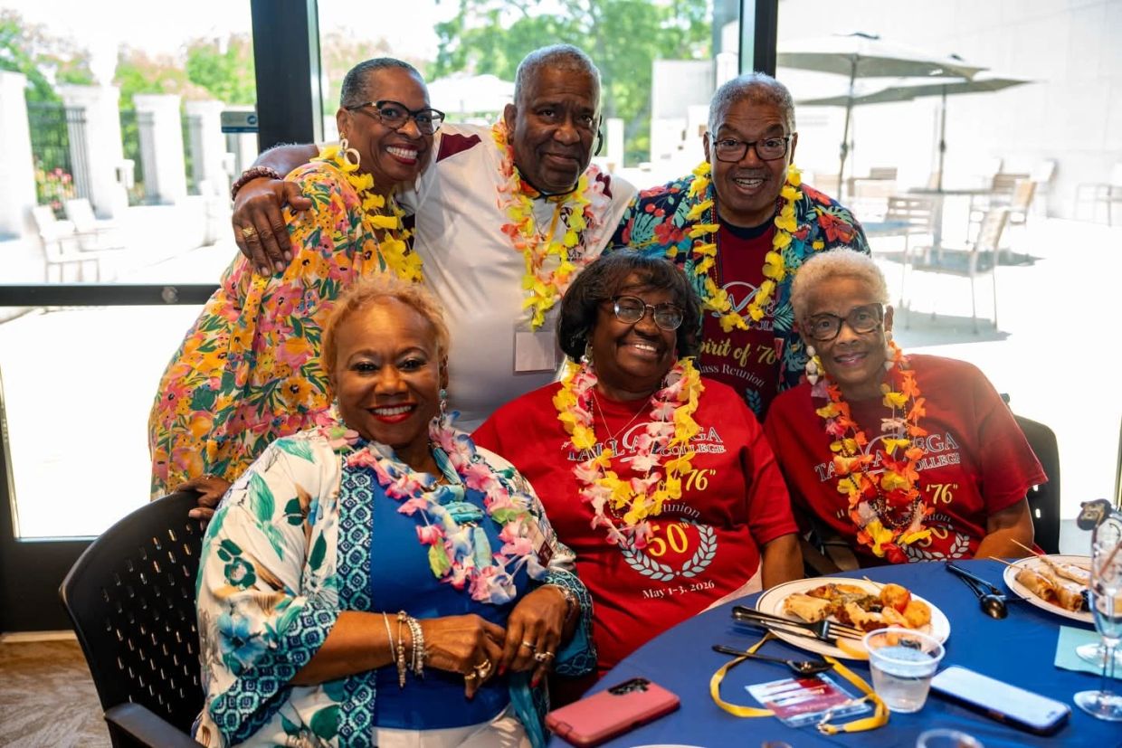 Group of seniors smiling and enjoying a reunion with leis and vibrant clothing.