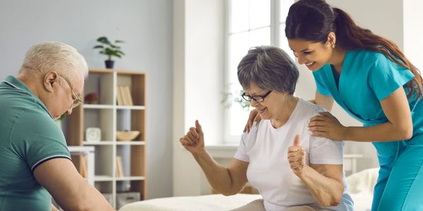 Elderly woman receiving physical therapy with a nurse's support at home.