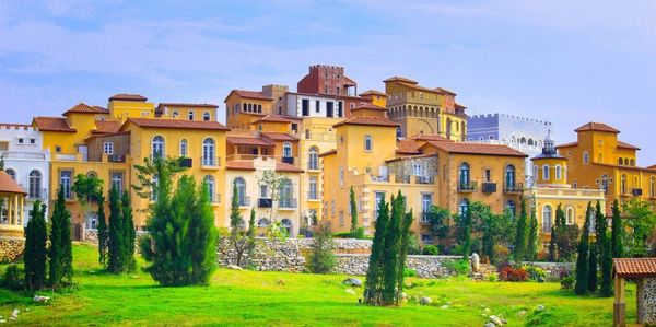 Colorful Mediterranean-style buildings with lush greenery in front under a clear sky.
