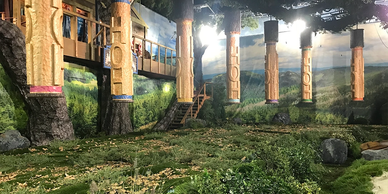 Indoor artificial landscape with tree-like pillars and a painted backdrop.
