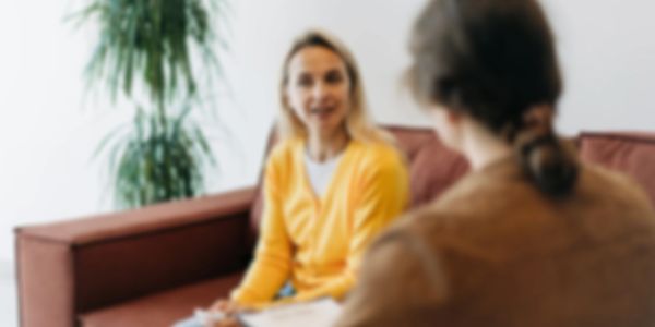 Two people engaged in a conversation on a couch in a cozy setting.