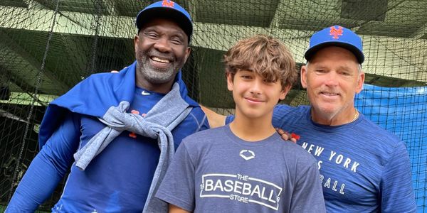 Three people, two men and a boy, posing with baseball gear indoors.