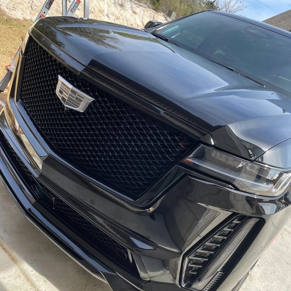 A sleek black Cadillac SUV parked outdoors with a shiny front grill.