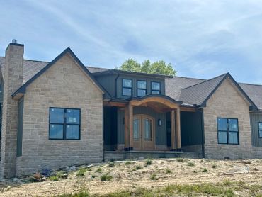 Modern stone house with wooden accents and large windows under a clear sky.