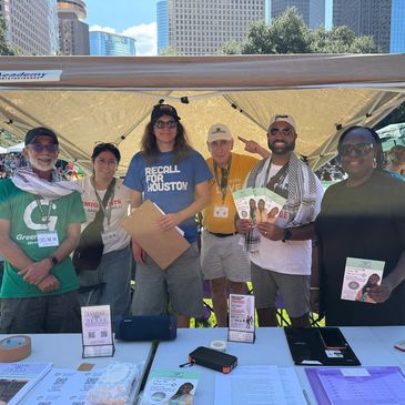 Group of six people at an outdoor advocacy booth in a city plaza.