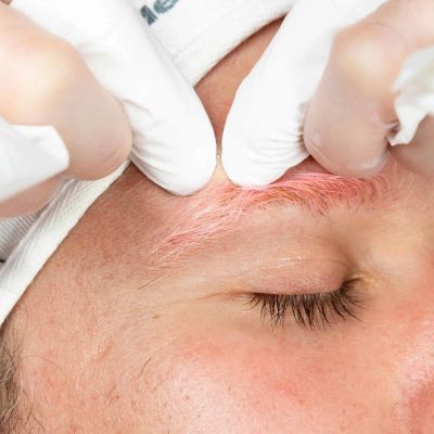 Close-up of someone grooming a pink eyebrow.