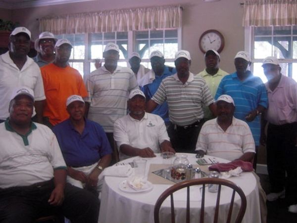 four people sitting and a group of people standing behind 