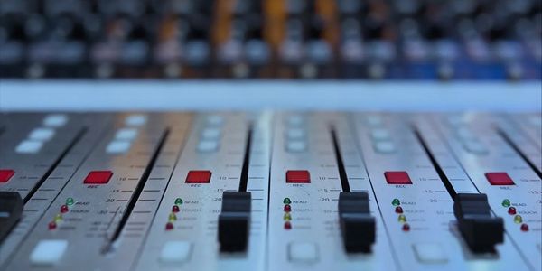 Close-up of audio mixing console sliders and buttons.