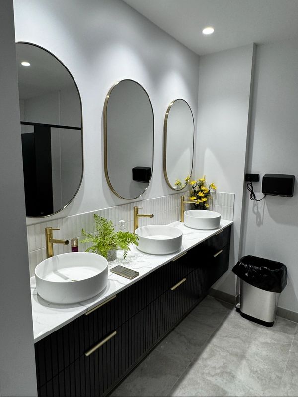 Modern bathroom with three oval mirrors and round sinks.