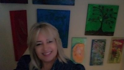 A smiling woman with blonde hair in front of colorful wall art.