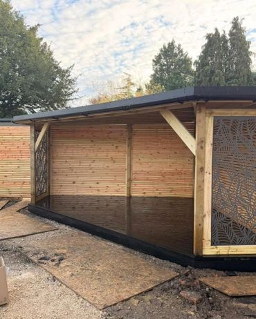 Newly constructed wooden garden shelter with decorative metal panels.
