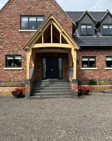 Brick house with wooden porch and black door.