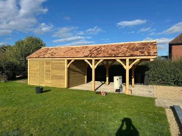 Wooden garden shed with a carport on a sunny day.