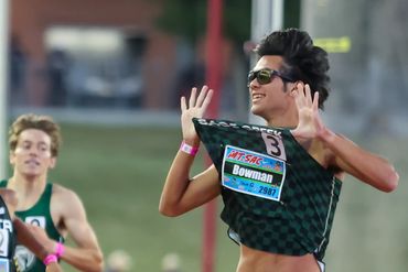 Runner celebrating victory during a race with a big smile and raised hands.