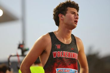 Young male athlete wearing a Wolverines running jersey during a track event.
