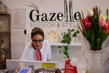 Woman working at a fashion and style store counter.