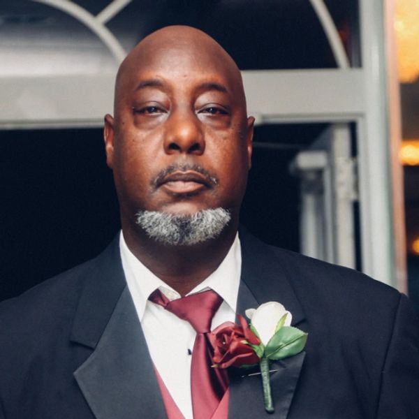 Man in formal suit with red tie and boutonniere.