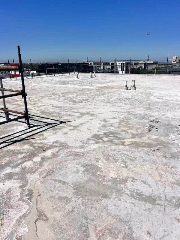 Concrete rooftop under clear blue sky with scaffolding.