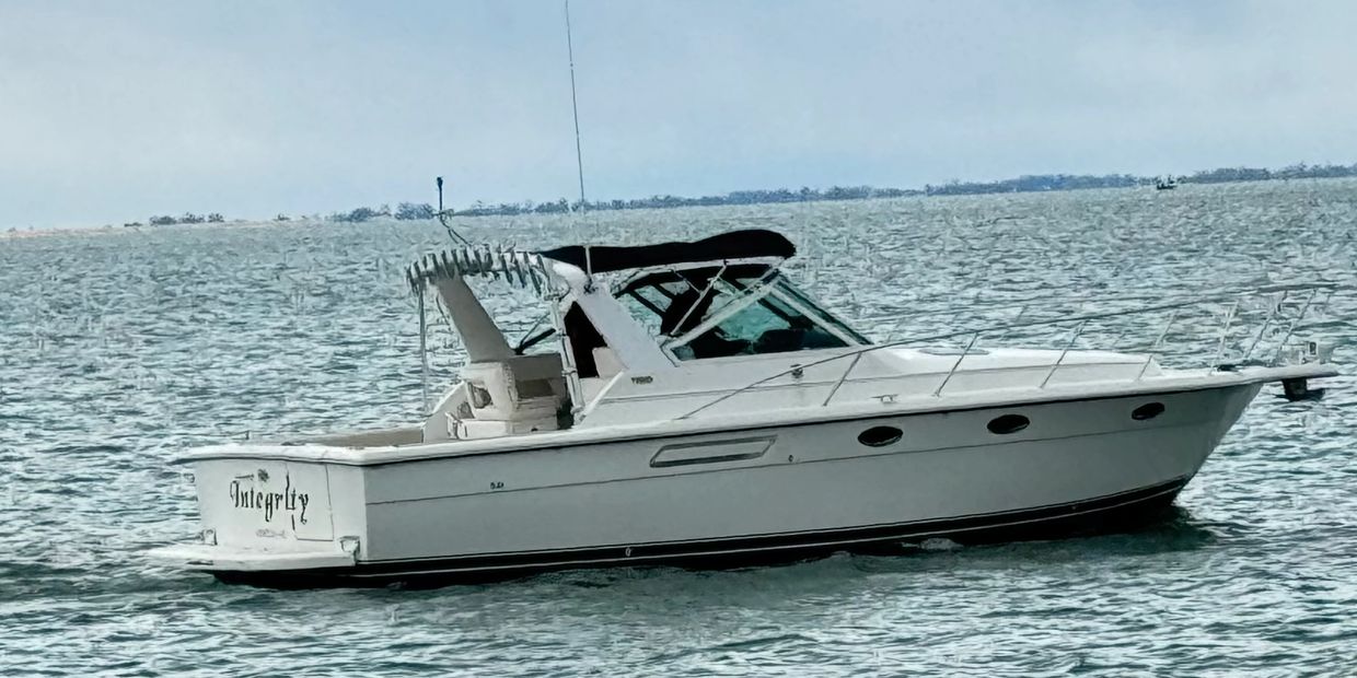 White motorboat named "Integrity" floating on calm water under a clear sky.