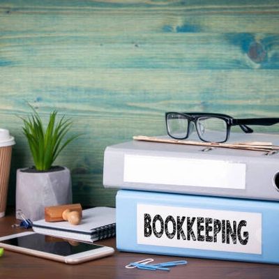 Bookkeeping folders, glasses, and office supplies on a desk.