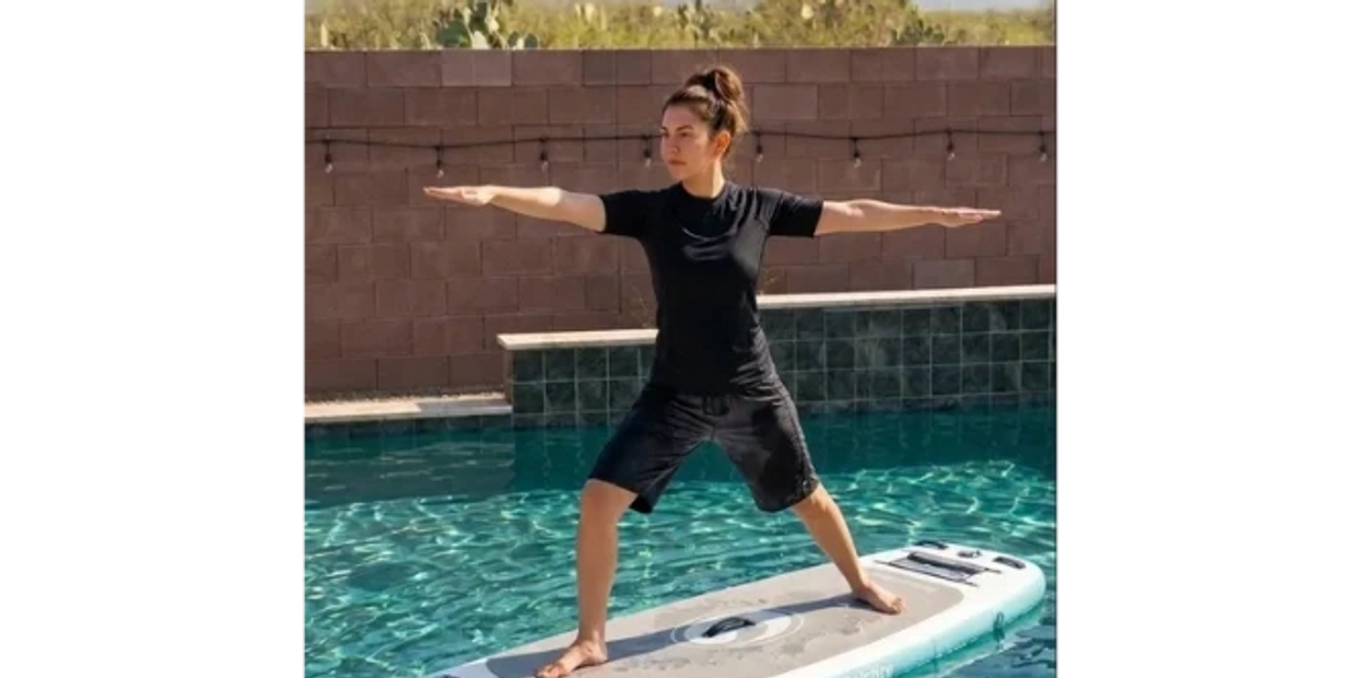 Woman practicing yoga on a paddleboard in a pool.