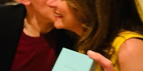Two people smiling, one holding a small blue box.