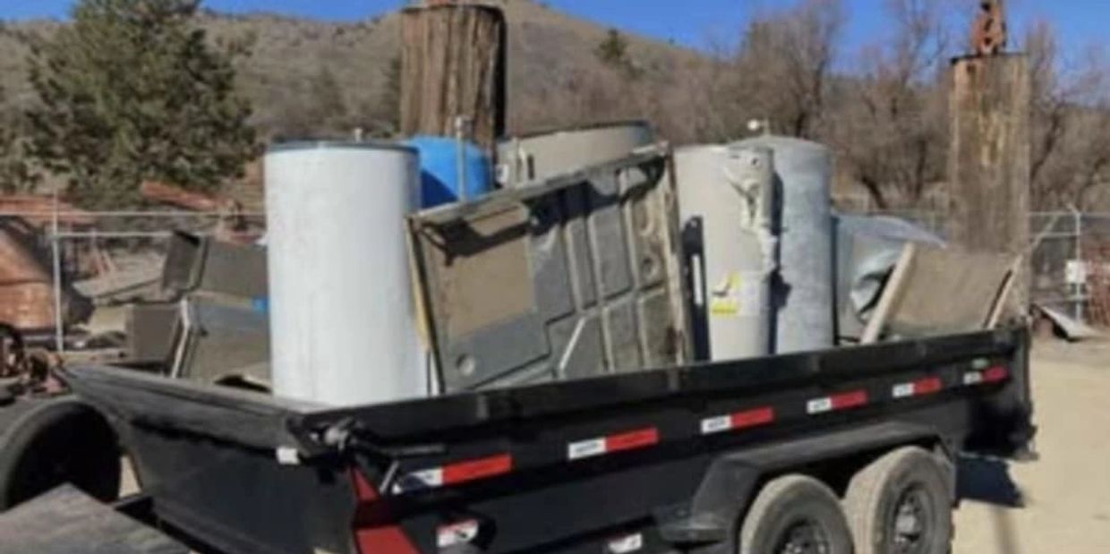 Trailer loaded with old appliances and metal scraps outdoors.