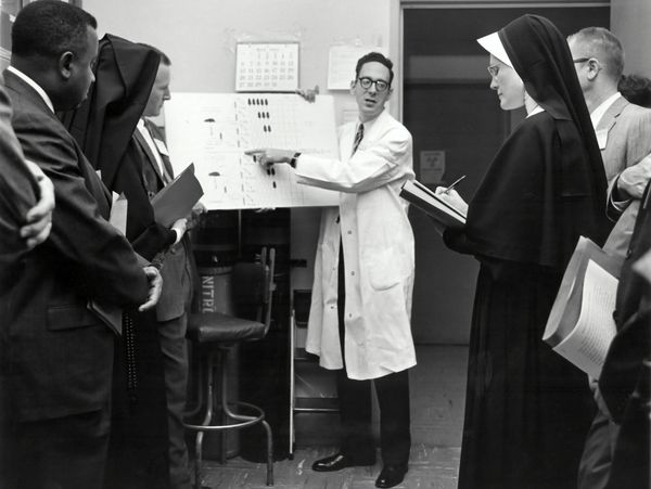 Doctor presenting research to nuns (black and white, National Cancer Archive on Unsplash.com)