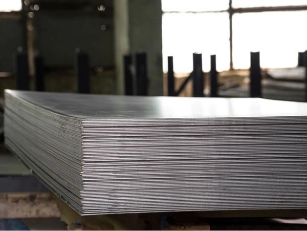 A stack of shiny metal sheets in an industrial setting.