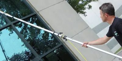 A man using high pressure water window cleaning tool to clean exterior windows