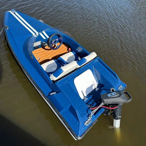 Blauwe Spitfire glasvezel speedboot met witte racingstrepen en houten dashboard, gezien van bovenaf op het water.