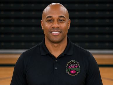 Smiling man in a black polo shirt with a sports logo.