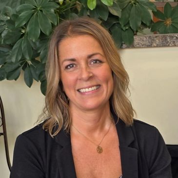 Smiling woman with blonde hair wearing a black jacket.