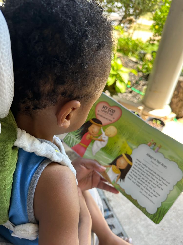 A child reading a colorful religious-themed book outdoors.