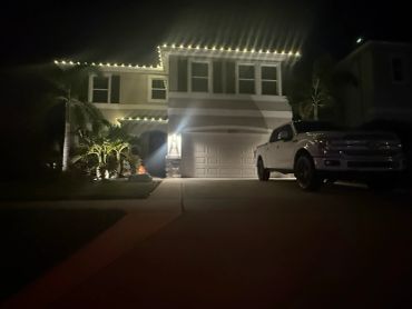 House decorated with lights and a white truck in driveway at night.