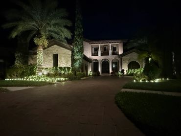 Luxury house with lights and palm trees at night.