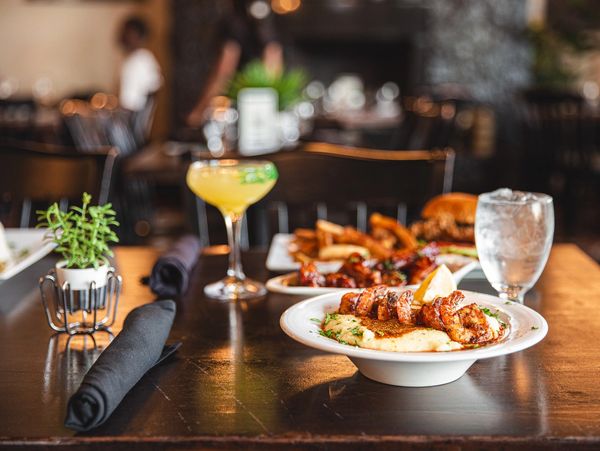 A delicious meal with skewers, fries, burger, and a cocktail.