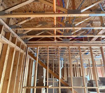 Wooden framework with metal connectors and electrical wiring inside a building under construction.