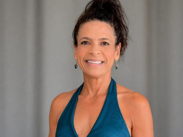 Smiling woman in a teal halter dress with dangling earrings.